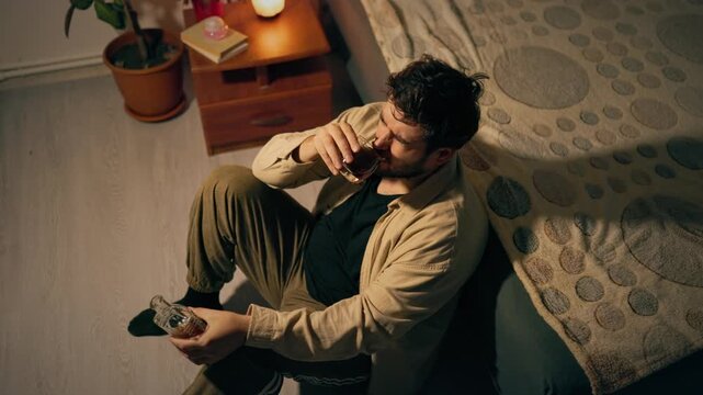 Alcohol abuse and mental exhaustion overwhelm distressed male on floor. Profound life crisis pain
