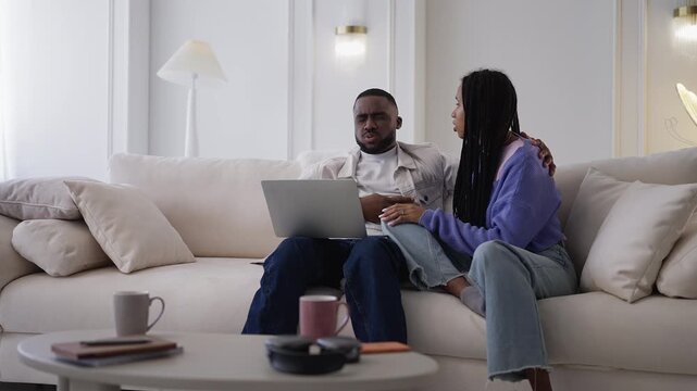 Upset African American couple read bad news email on laptop, funding denied