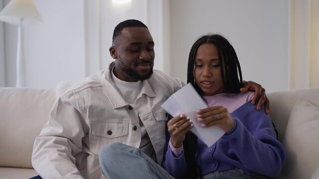 Young Black couple read good news letter, celebrating application approval