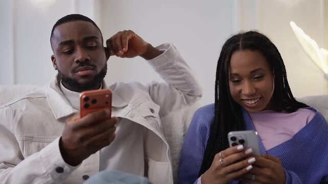 Young Black woman and her boyfriend typing on phones, screen dependency