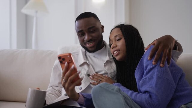 Smiling African American couple scroll on phone while shopping online together