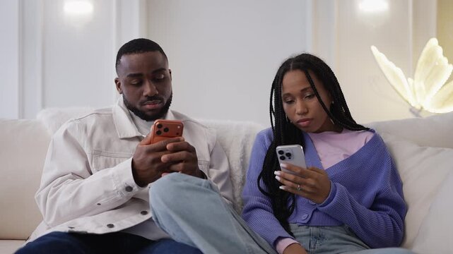 Young African American couple scrolling on their phones, gadget dependency