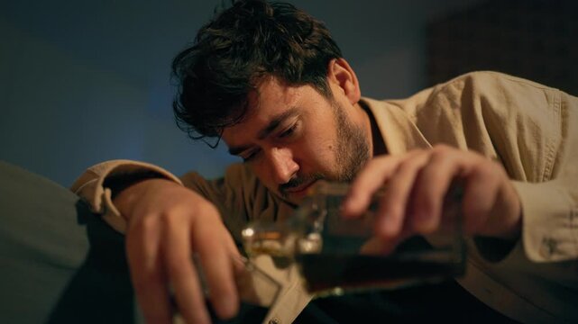 Alcohol dependency causes heartbroken adult male to drink whiskey on rug. Deep depression and pain