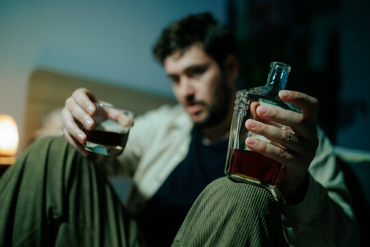 Adult male struggles with daily anxiety holding alcohol in darkness. Major life heartbreak grief