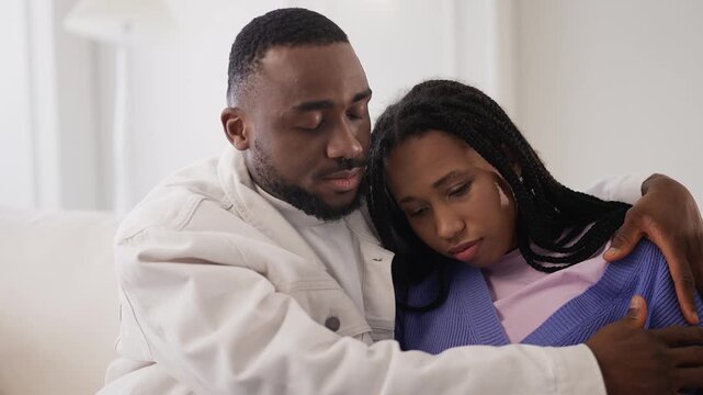 Caring African American man hugs and supports upset girlfriend at home