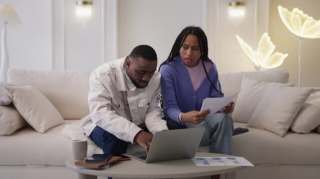 Black couple analyze taxes and financial reports on laptop at home