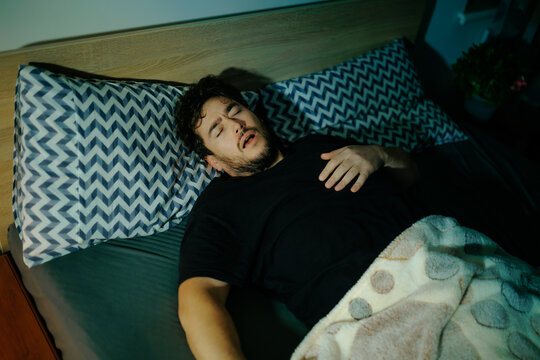 Traumatized male lies in dark bedroom surviving fear and chronic insomnia. Extreme grief terror