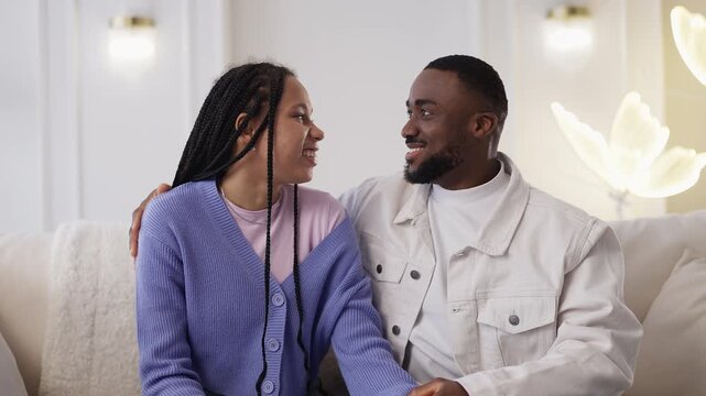 Portrait of cheerful African American couple embracing at home, in love