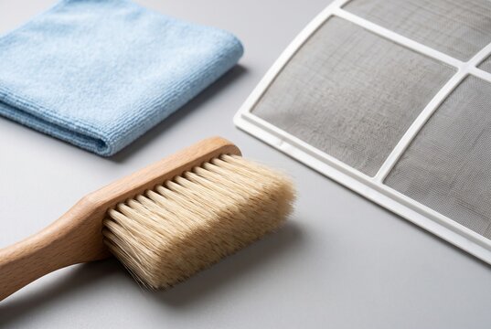 Cleaning brush and blue microfiber cloth beside air conditioner filter