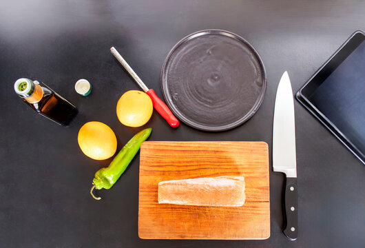 Cooking fresh salmon fillet using online recipe on digital tablet