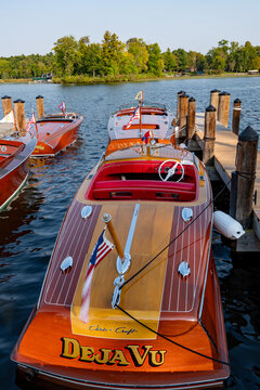 NISSWA, MN - 12 SEP 2024: Overhead stern view of classic Chris-Craft mahogany speedboat Deja Vu with honey wood, white inlays, red interior, chrome, and American flag at Lake Nisswa boat show.
