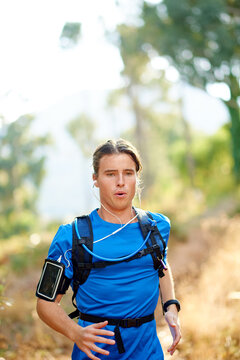 Outdoor, man and music with running for fitness, breathing and runner with training for marathon. Nature, male person and athlete with hydration pack for wellness, endurance and earphones for workout
