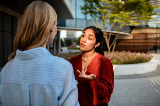 Woman gesturing while talking to another woman outside an office