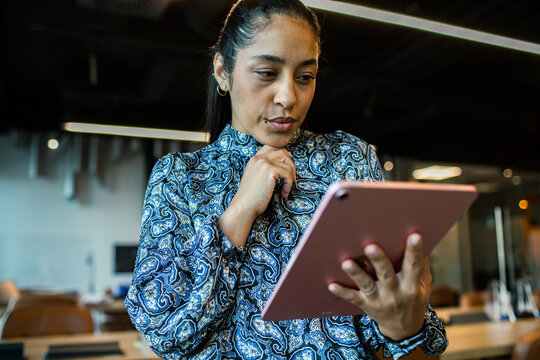 Thoughtful businesswoman using tablet in modern office