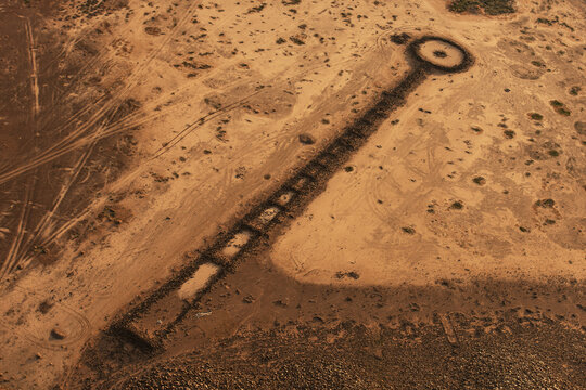 Aerial view of ancient prehistoric ring cairns in the desert landscape, featuring stone structures and geometric patterns across the arid terrain in Khaybar, Al Madinah, Saudi Arabia.