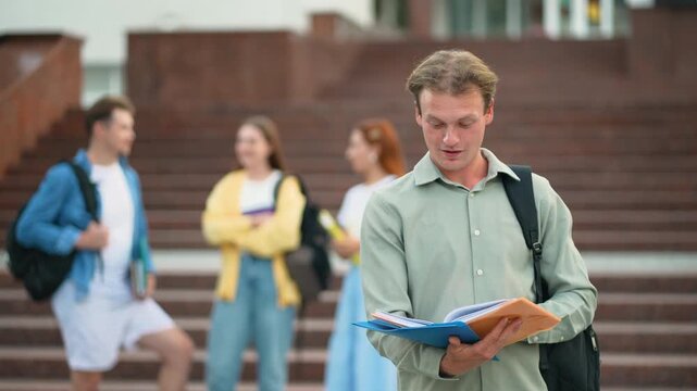 Male university student studying before looking up and smiling