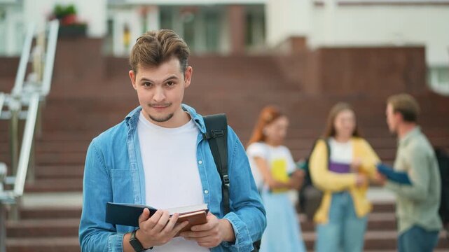Smiling male student reading book showing thumbs up
