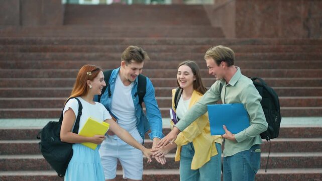 Team of students joining hands in celebration