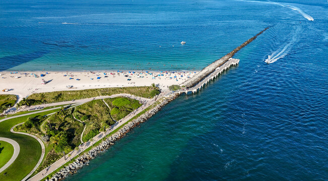 Aerial view of Government Cut jetty extending into the Atlantic Ocean with a sandy beach, turquoise water, and boats in Miami-Dade County, Florida, United States.