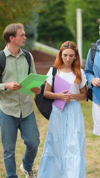 University students talking and walking together on campus green lawn