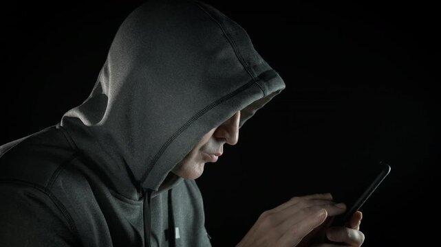 Male stealing passwords on phone. A man hacker working with personal password on smartphone against black background