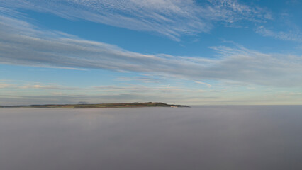 Fototapeta premium Lewes aerial photography featuring morning fog, rolling hills, cloudscape, sky, nature, cinematic perspective, terrain, landscape, and breathtaking panorama during an early flight.
