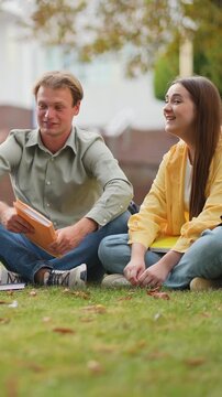 Two university students studying together on campus lawn