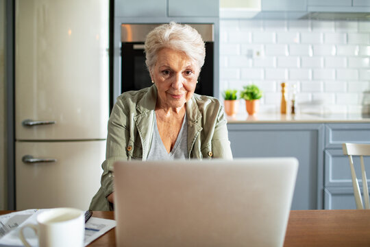 Senior woman using laptop at kitchen table