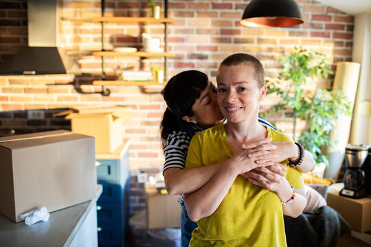 Woman kissing partner from behind while unpacking at home