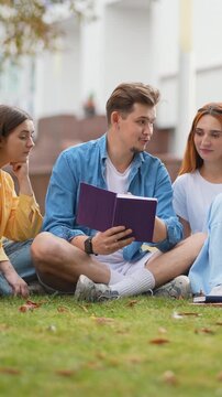 Group of university students reading together on campus lawn