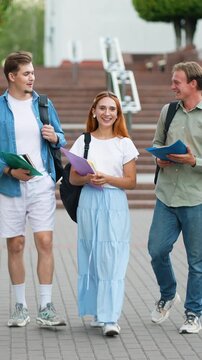Group of college students walking and talking on university campus