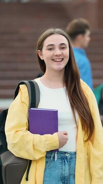 Young female student with backpack smiling at camera