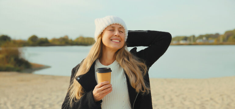Stylish happy woman standing on beach, girl smiles, looking away on sea