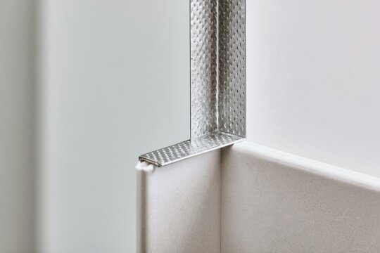 Close up view of metal corner bead installation for drywall edge reinforcement in interior construction work