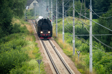 Historic TKt48 steam locomotive pulling a retro passenger train on the railway tracks near Chabowka, Poland © lumofoto
