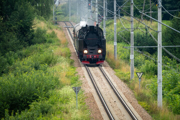 Historic TKt48 steam locomotive pulling a retro passenger train on the railway tracks near Chabowka, Poland © lumofoto
