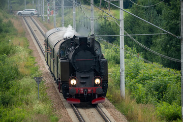 Historic TKt48 steam locomotive pulling a retro passenger train on the railway tracks near Chabowka, Poland © lumofoto