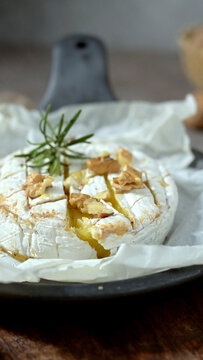 Baked camembert cheese topped with walnuts and rosemary on parchment paper