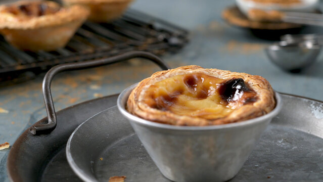 Freshly baked Portuguese pastel de nata egg custard tart in a metal baking mold on a tray