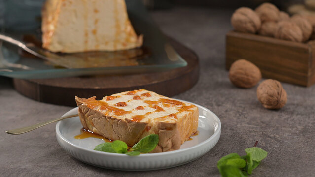 Slice of Portuguese P&atilde;o de L&oacute; sponge cake drizzled with caramel sauce and garnished with fresh mint on a plate