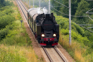Historic TKt48 steam locomotive pulling a retro passenger train on the railway tracks near Chabowka, Poland © lumofoto