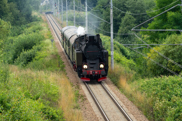 Historic TKt48 steam locomotive pulling a retro passenger train on the railway tracks near Chabowka, Poland © lumofoto