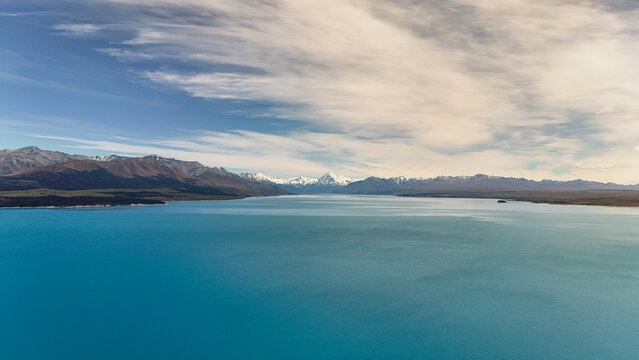 Aerial view of the turquoise waters of Lake Pukaki with the snow-capped Southern Alps and Aoraki Mount Cook in the distance, Ben Ohau, Canterbury Region, New Zealand.