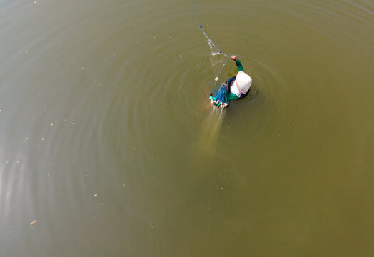 Aerial view of a fisherman casting a net into the water at Toyareja, Purbalingga, Central Java, Indonesia.