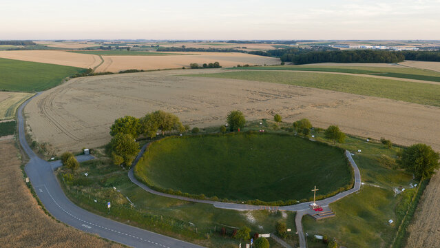 Aerial view of Lochnagar Crater WW1, a large historic mine crater surrounded by agricultural fields and trees in Ovillers-la-Boisselle, Hauts-de-France, France.