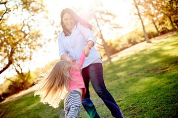 Fototapeta premium Mom, spin girl and happy at park with game, bonding and child with love, care and summer in nature. People, mother and daughter in garden with smile, swing or play for family fun in New Zealand