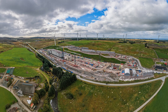 Aerial view of the Green Mountain data center construction site with industrial buildings, heavy machinery, and wind turbines in Undheim, Rogaland, Norway.
