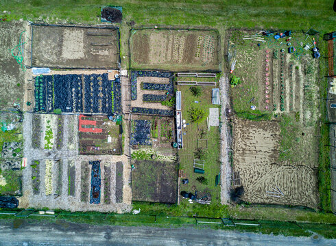Aerial view of a community garden with various vegetable plots, raised beds, and soil patches in Dutchess County, New York, United States.
