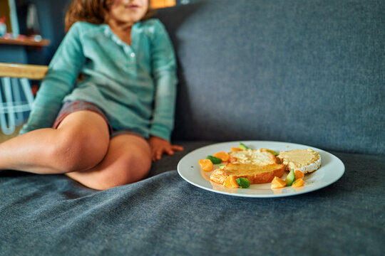 Boy Sitting on a Sofa With a Plate of Toast, Hummus and Fruit
