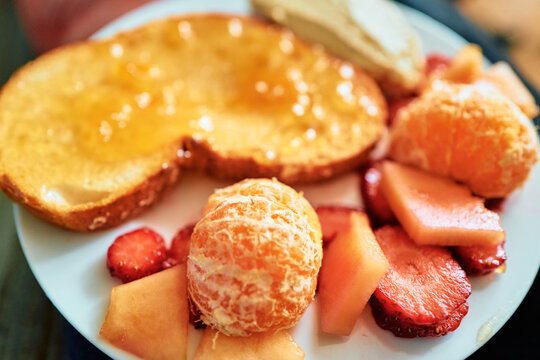 Honey Toast With Sliced Strawberries and Peeled Mandarin on a White Plate